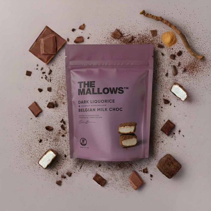 Purple packaging of 'The Mallows' Dark Liquorice with chocolate pieces around on a light background